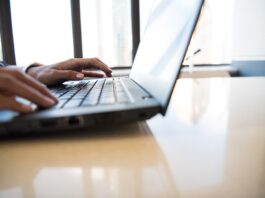 person using black laptop on brown table