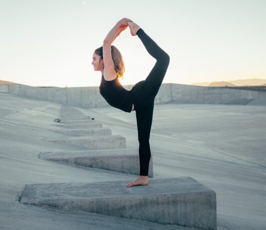 shallow focus photo of woman in black sleeveless shirt doing yoga