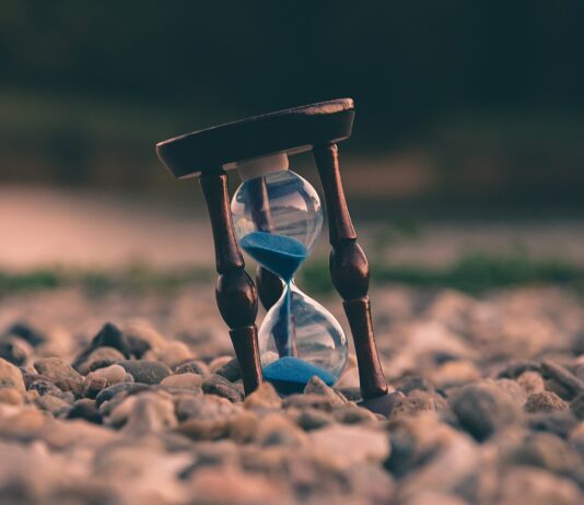 selective focus photo of brown and blue hourglass on stones