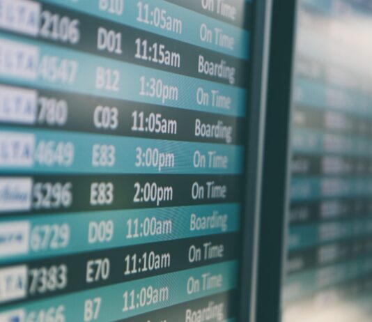 Airport departures timetable showing Delta and Alaska Airlines flights on time and boarding