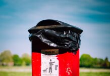 red and black trash bin on green grass field during daytime