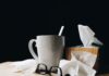 white ceramic mug on white table beside black eyeglasses